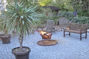 A circular outdoor seating area with a fire pit, a bench, and potted plants. - Holiday apartment with 2 bedrooms (Amelinghausen)