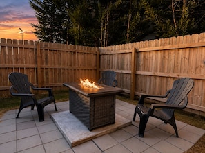 An outdoor patio with a fire feature, two chairs, and a wooden fence. - New Pige Forge Condo | Steps to Parkway (Pigeon Forge)