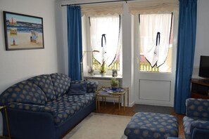 Uma sala de estar com sofá, uma mesinha e televisão.