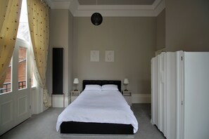 A hotel room with a large bed, two bedside tables with lamps, a radiator, and two framed artworks on the wall. - Historic Hull Old Town Apartment (Kingston upon Hull)