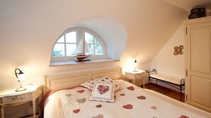 A bedroom with a bed, a window, a bedside table, and a wardrobe.