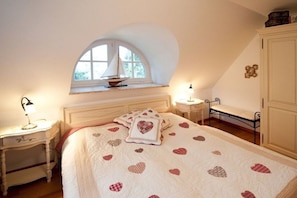 A bedroom with a bed, a window, a bedside table, and a wardrobe.