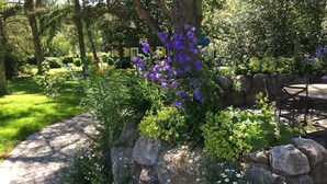 A garden with a stone wall, a tree, and a patio area with outdoor furniture.