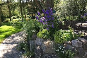 A garden with a stone wall, a tree, and a patio area with outdoor furniture.