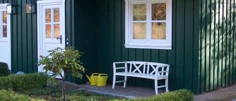 A green building with a white bench and a small tree.