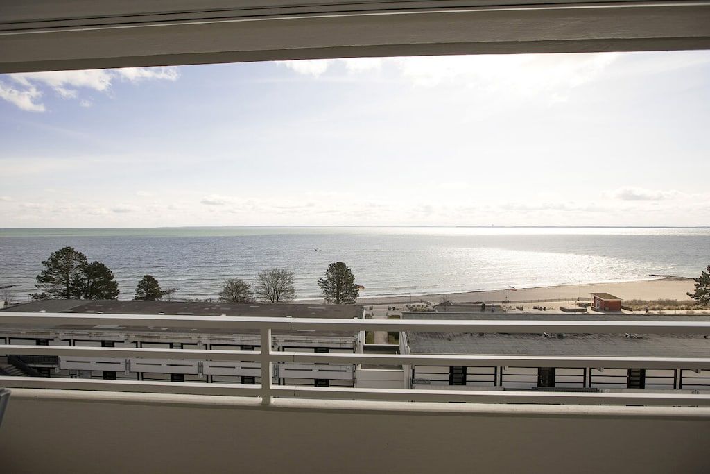 Vista desde una ventana sobre una playa con cielo despejado.