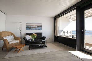 A modern living room with a sofa, coffee table, and a painting on the wall. - Holiday apartment in Sierksdorf with parking (Sierksdorf)