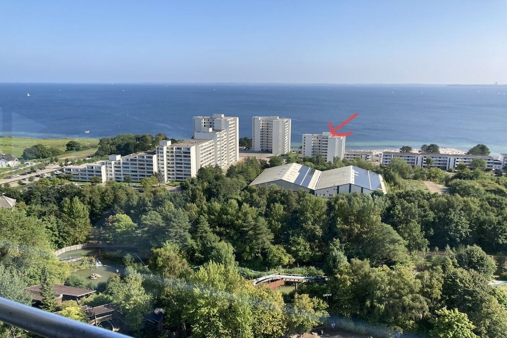A coastal residential area with multiple high-rise buildings, a body of water, and a forested area.
