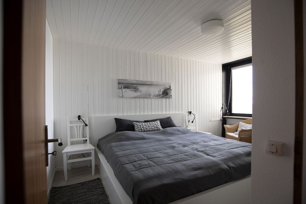 Een slaapkamer met een bed, nachtkastje, lamp en een raam.
