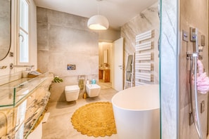 Ein modernes Badezimmer mit einer Duschkabine aus Glas, einer freistehenden Badewanne und einem мраморном Waschtisch.