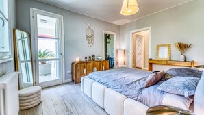 Een slaapkamer met een bed, nachtkastjes, een dressoir, een dromenvanger en een raam.