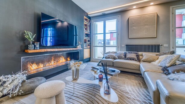 Een moderne woonkamer met een open haard, een bank, een salontafel en een televisie.