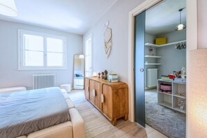 A bedroom with a bed, a wooden dresser, a mirror, and a wardrobe.