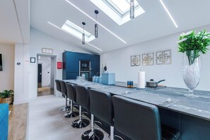 Una cocina moderna con una barra alargada, iluminación sobre la encimera y vistas al área de comedor.