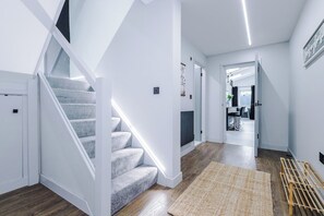 A modern interior with a staircase, a hallway leading to a dining area, and a view of the outdoors.
