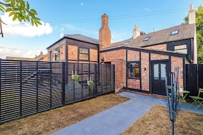 A residential property with a brick exterior, a black metal fence, and a paved driveway. - Stylish Home for 8 | Games Room & Free Parking (Northwich)