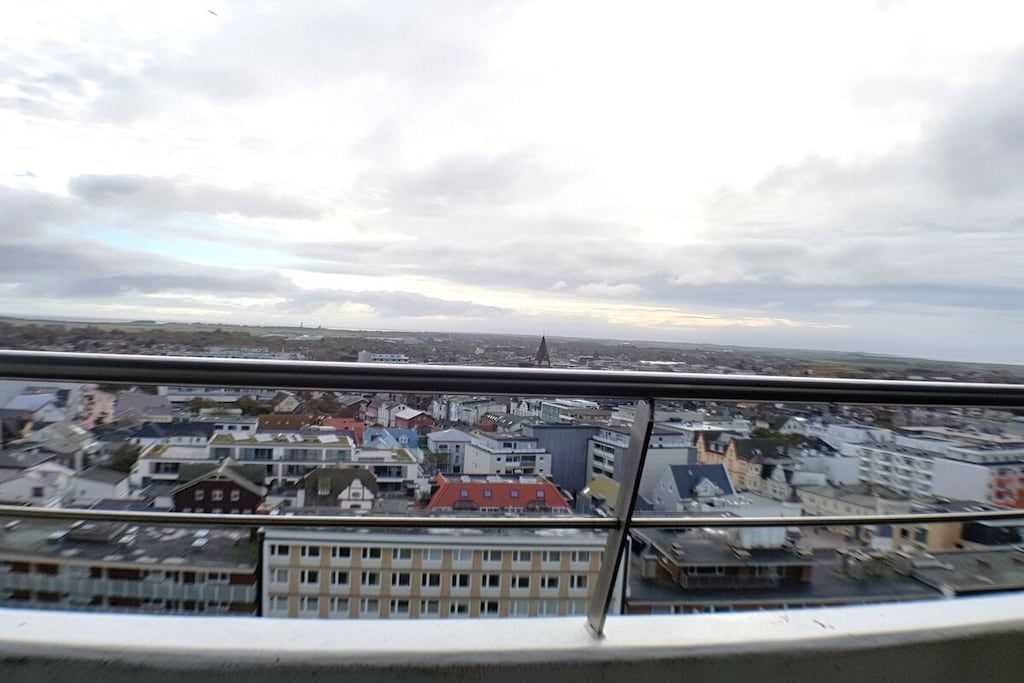 Ein Stadtbild, das von einem erhöhten Aussichtspunkt, vermutlich von einem Balkon oder Fenster, aus betrachtet wird.