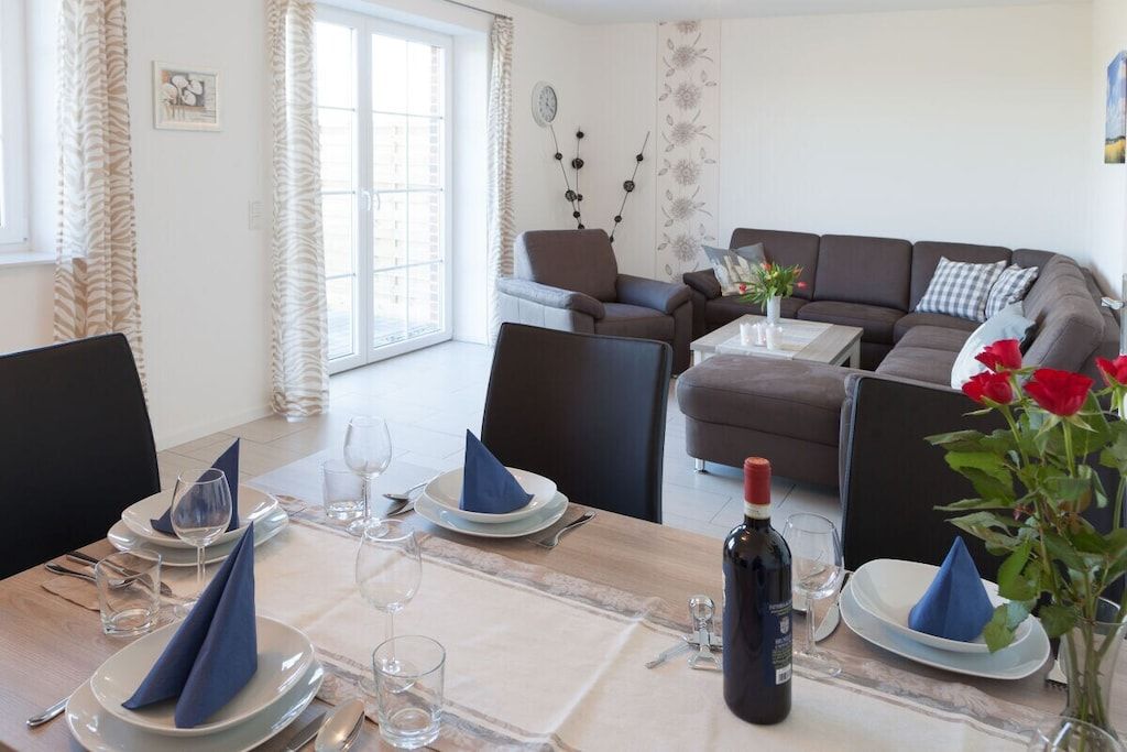 A dining area with a table set for two, a sofa, and a decorative wall piece.