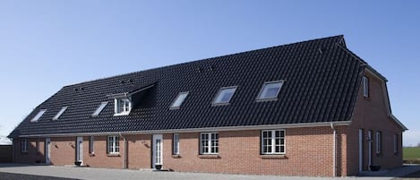 A two-story brick building with a sloped roof and multiple windows.