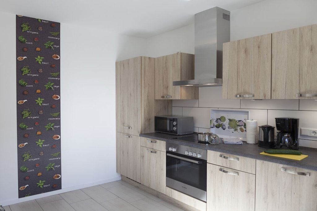 A modern kitchen with wooden cabinets, a microwave, a stove, and a coffee maker.