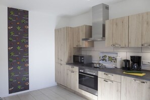 A modern kitchen with wooden cabinets, a microwave, a stove, and a coffee maker. - Holiday apartment in Boren with swimming pool (Boren)