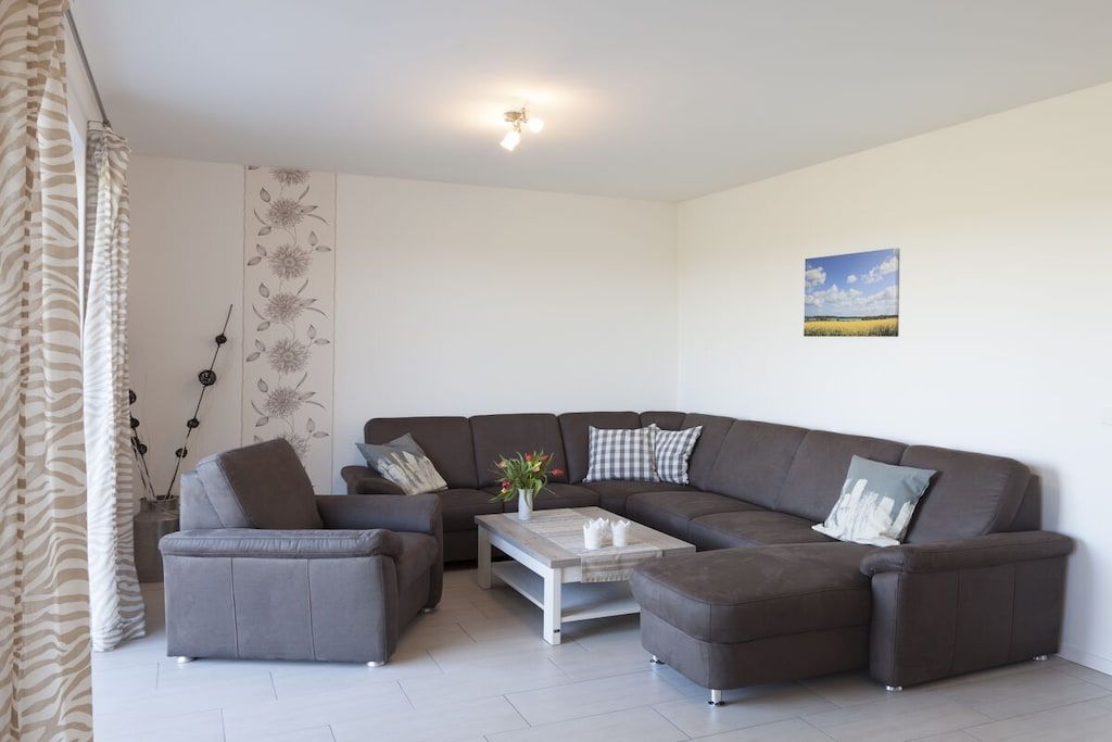 A modern living room with a grey sectional sofa, a matching armchair, and a coffee table.