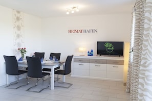 A dining area with a table, chairs, a TV, and a wall-mounted sign. - Holiday apartment in Boren with swimming pool (Boren)