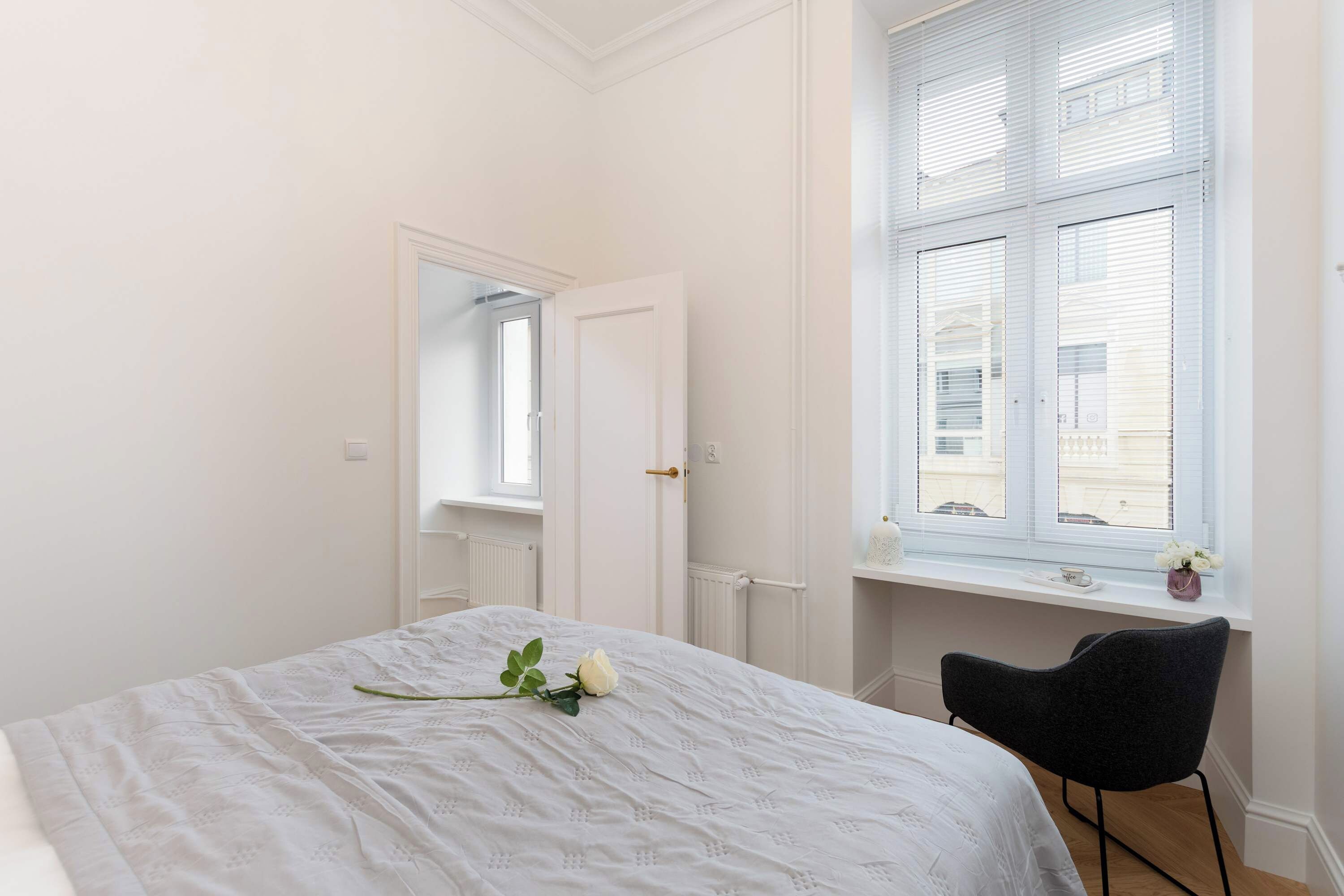 Ein Schlafzimmer mit einem Bett, einem Sessel, einem Fenster mit Jalousien und einer Heizung.
