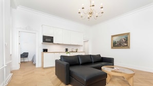 Ein modernes Wohnzimmer mit einem schwarzen Ecksofa, einem Glastisch und einer Pendelleuchte.