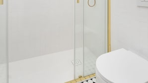 Ein modernes Badezimmer mit einer gläsernen Duschkabine, einer weißen Toilette und einem schwarz-weißen Fliesenboden.