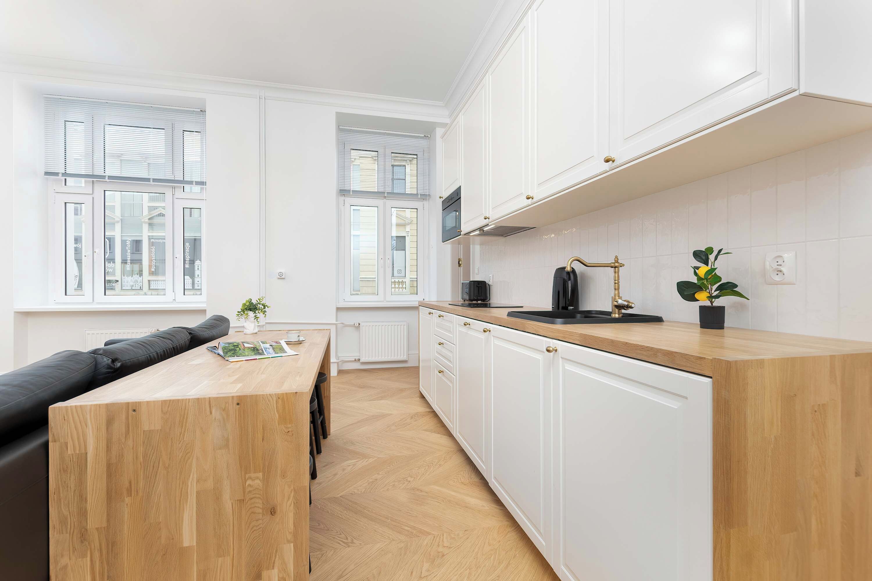 Una cocina moderna con armarios blancos, encimera de madera y horno integrado.