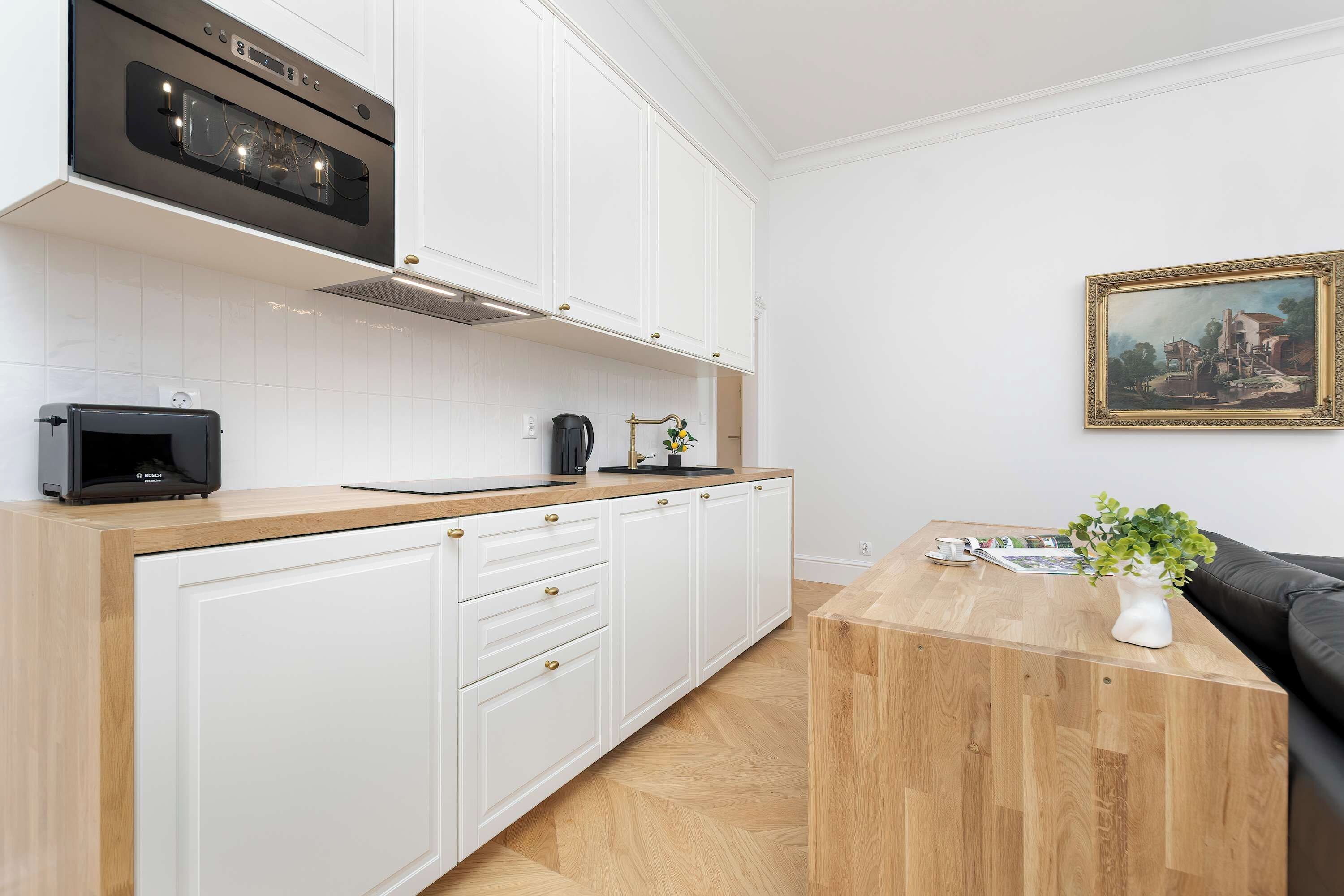 Una cocina moderna con armarios blancos, un tostador Bosch y una cafetera.