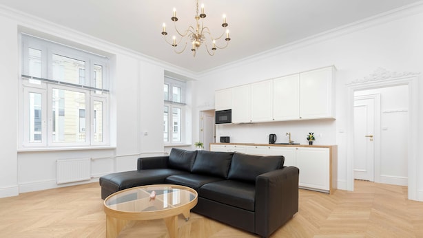 Ein modernes Wohnzimmer mit einem schwarzen Ledersofa, einem Glastisch und einer Kristallleuchtre.