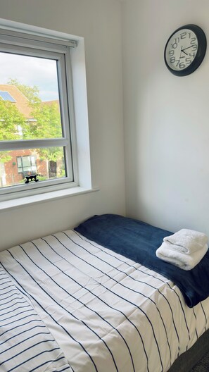 A bedroom with a bed, a window, and a wall-mounted clock. - Spacious 4-Bed Home for Families, Corporate & Groups | City Centre | Parking (Salford)
