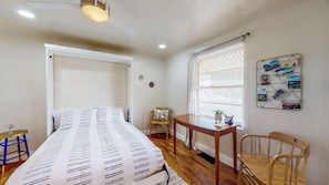 Un dormitorio con cama, escritorio, silla y ventana con persianas.