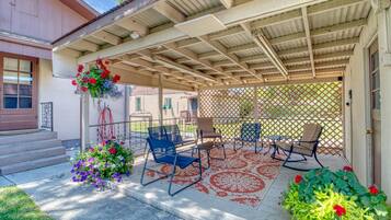 A covered patio with outdoor furniture, a decorative flower arrangement, and a lattice fence.