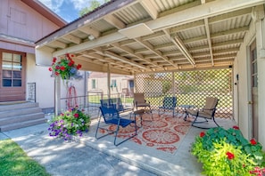 A covered patio with outdoor furniture, a decorative flower arrangement, and a lattice fence.