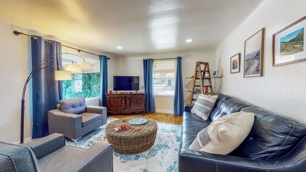 Una sala de estar con sofá, sillón, televisor, aparador de madera y estantería.