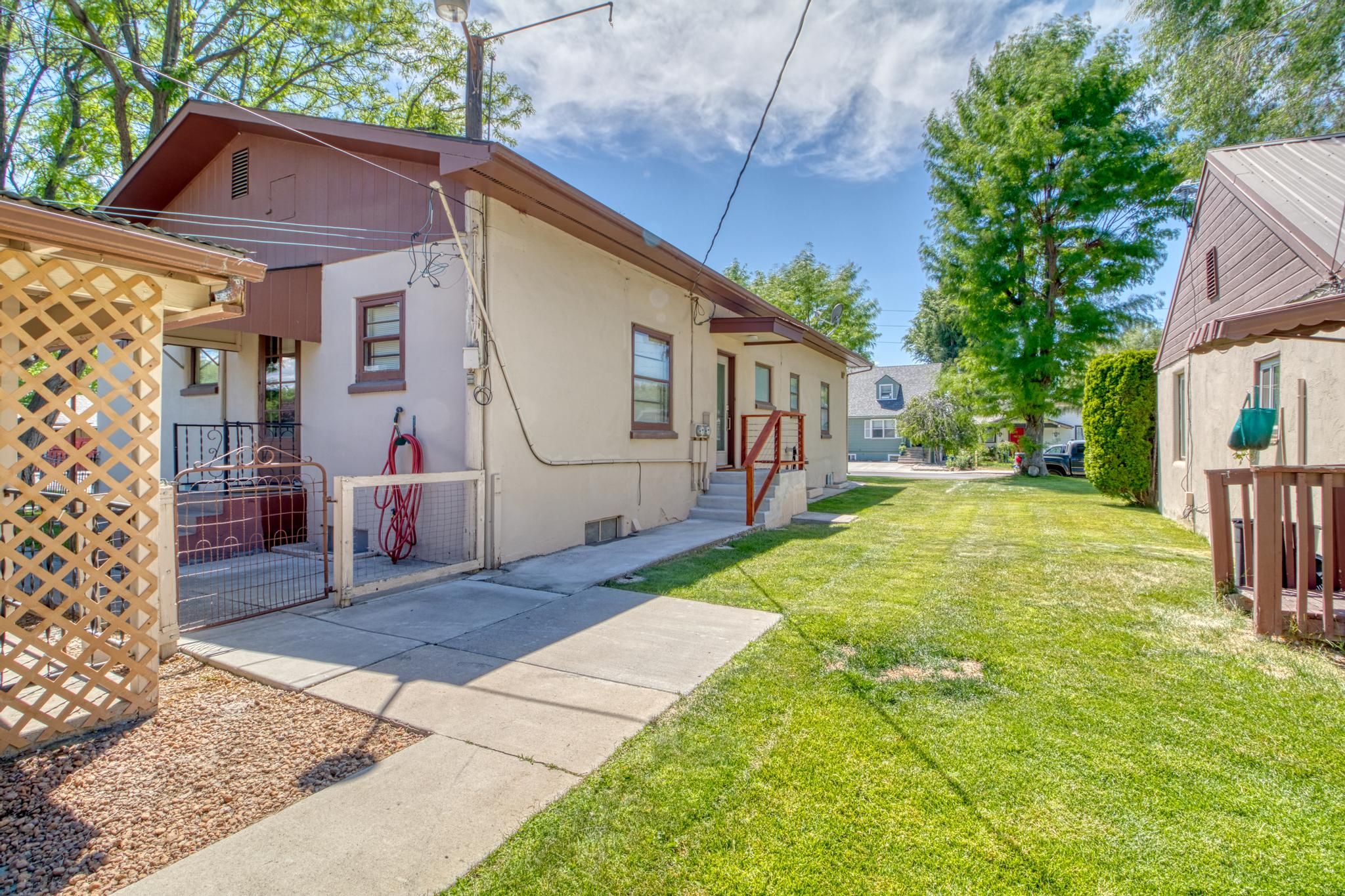 A residential property with a paved driveway, a small lawn, and a wooden fence.