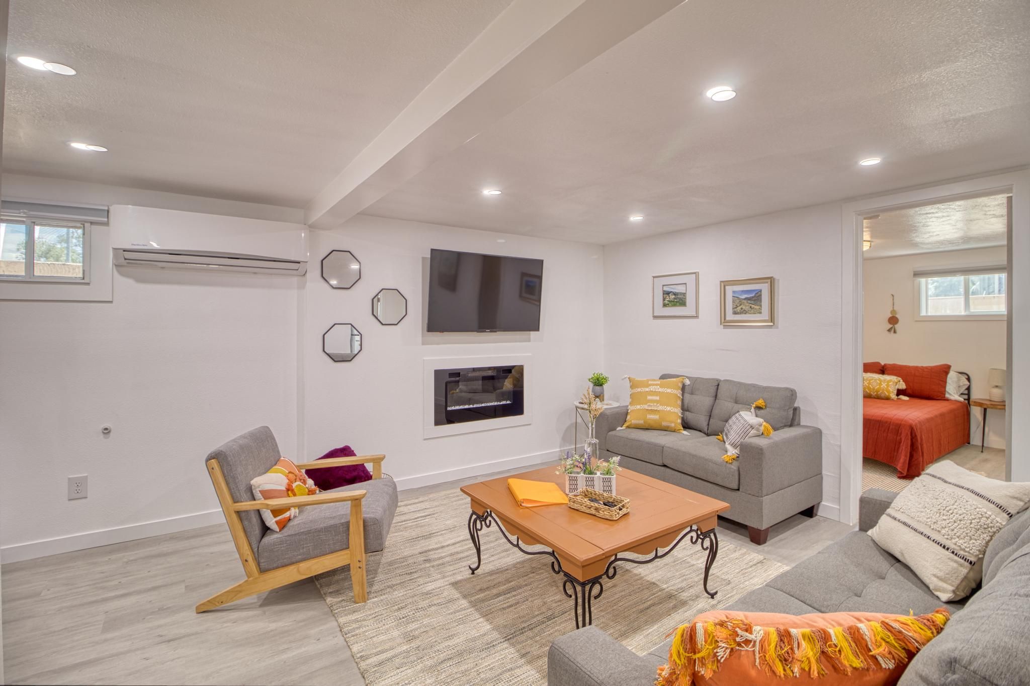 A modern living room with a grey sofa, a wooden coffee table, and a grey armchair.