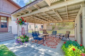 A covered patio with outdoor furniture, a decorative flower arrangement, and a lattice fence.