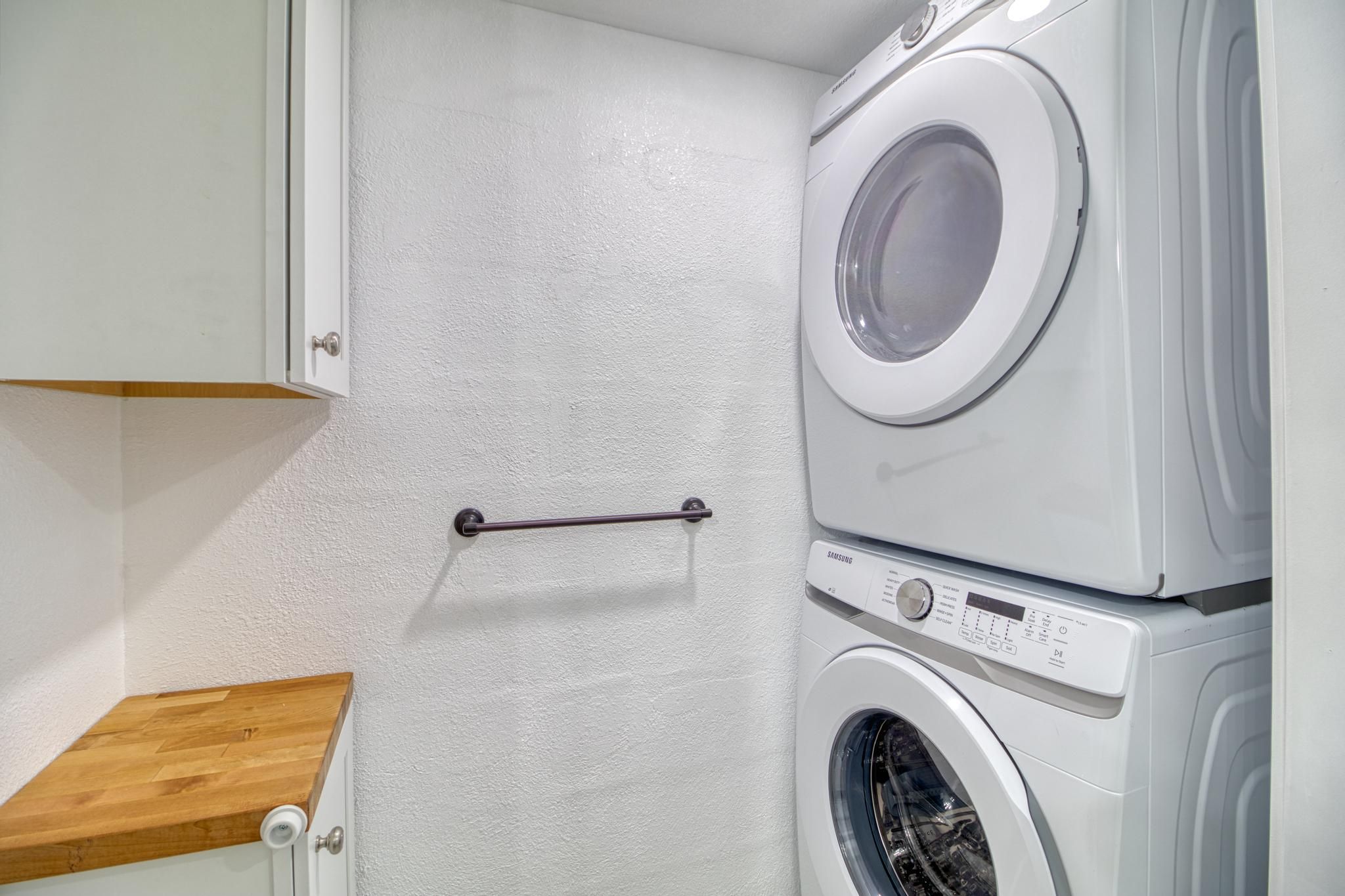 A laundry room with a washing machine and dryer stacked on top of each other.