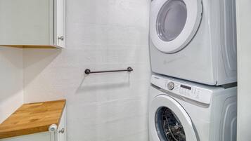 A laundry room with a washing machine and dryer stacked on top of each other.