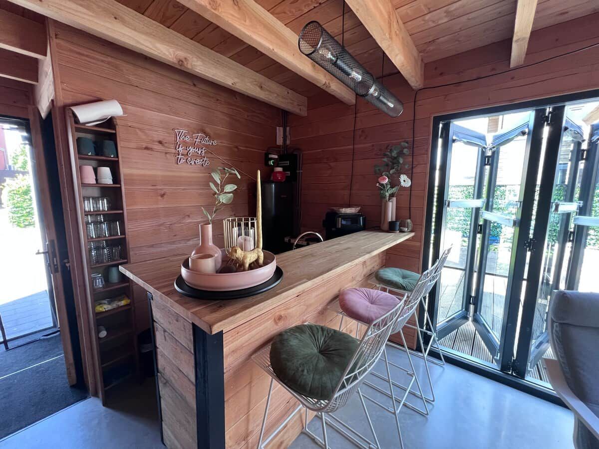 Ein Holzinterieur mit Barbereich, Sitzgelegenheiten und Blick durch große Glasfenster.