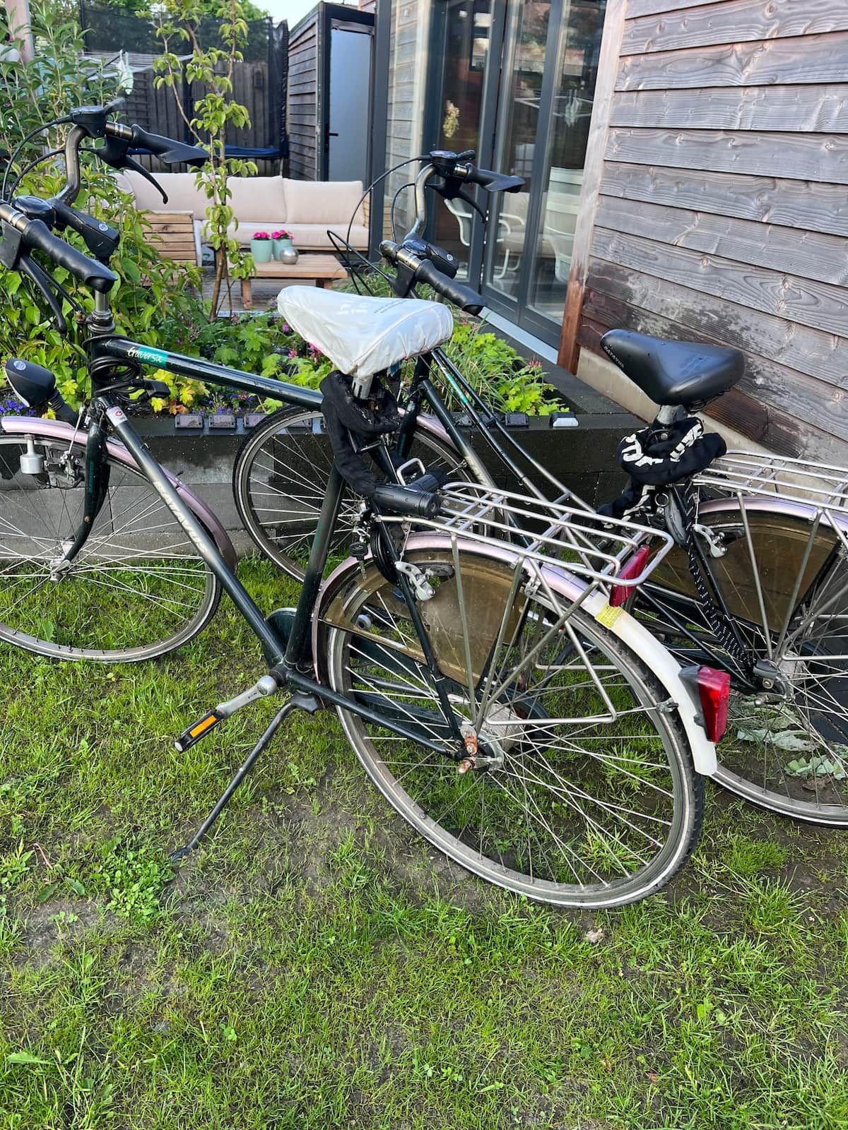 Ein Fahrrad steht auf einer Rasenfläche mit einem Holzzaun und einem Gebäude im Hintergrund.