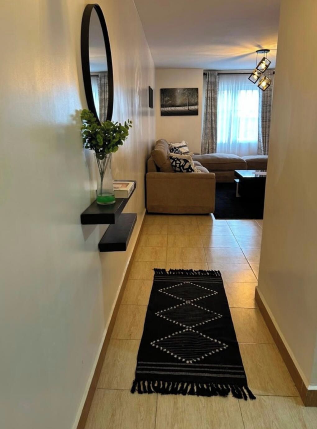 A hallway with a black rug, a sofa, a coffee table, and a mirror on the wall.