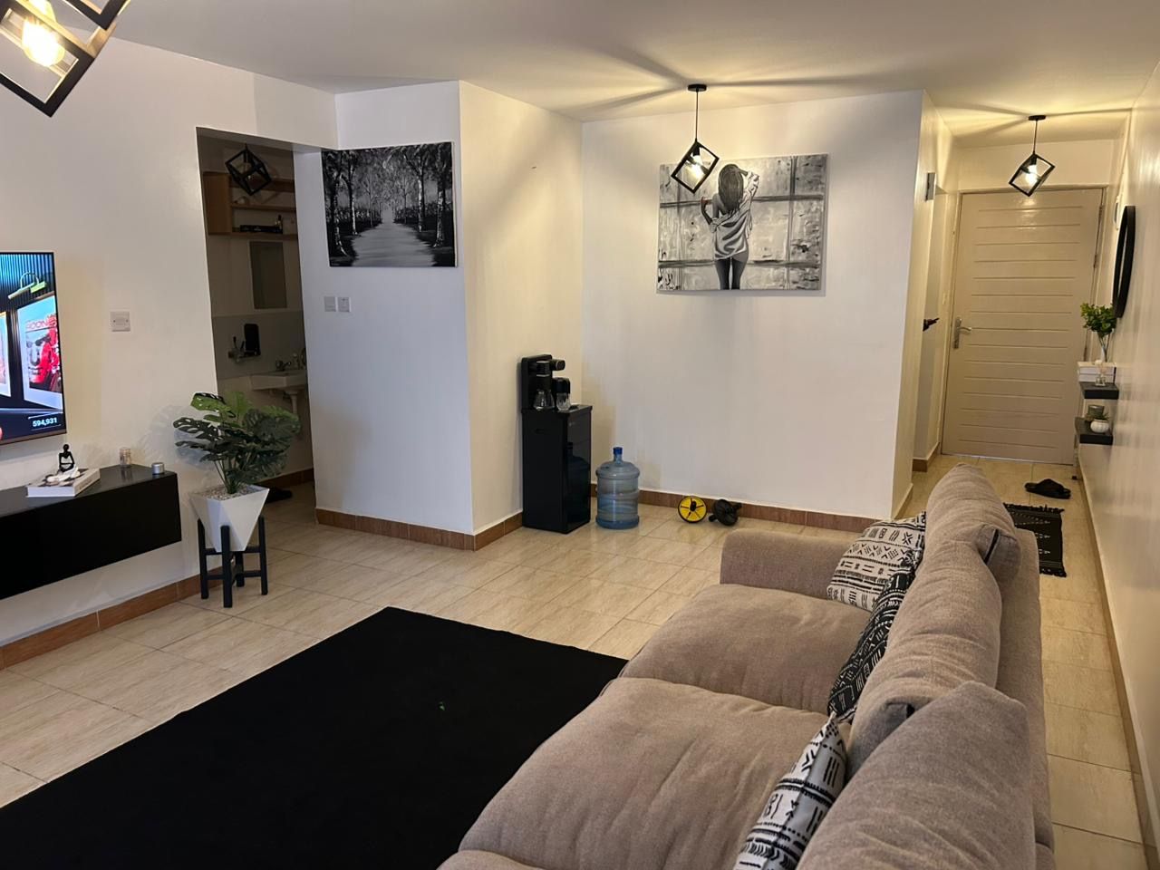 Een woonkamer met een bank, een salontafel, een televisie en een schilderij aan de muur.