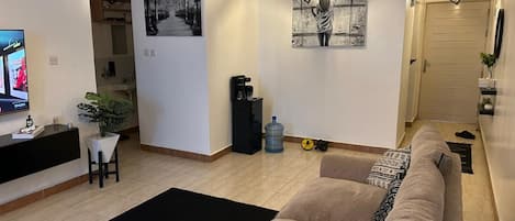 A living room with a sofa, a coffee table, a TV, and a painting on the wall.