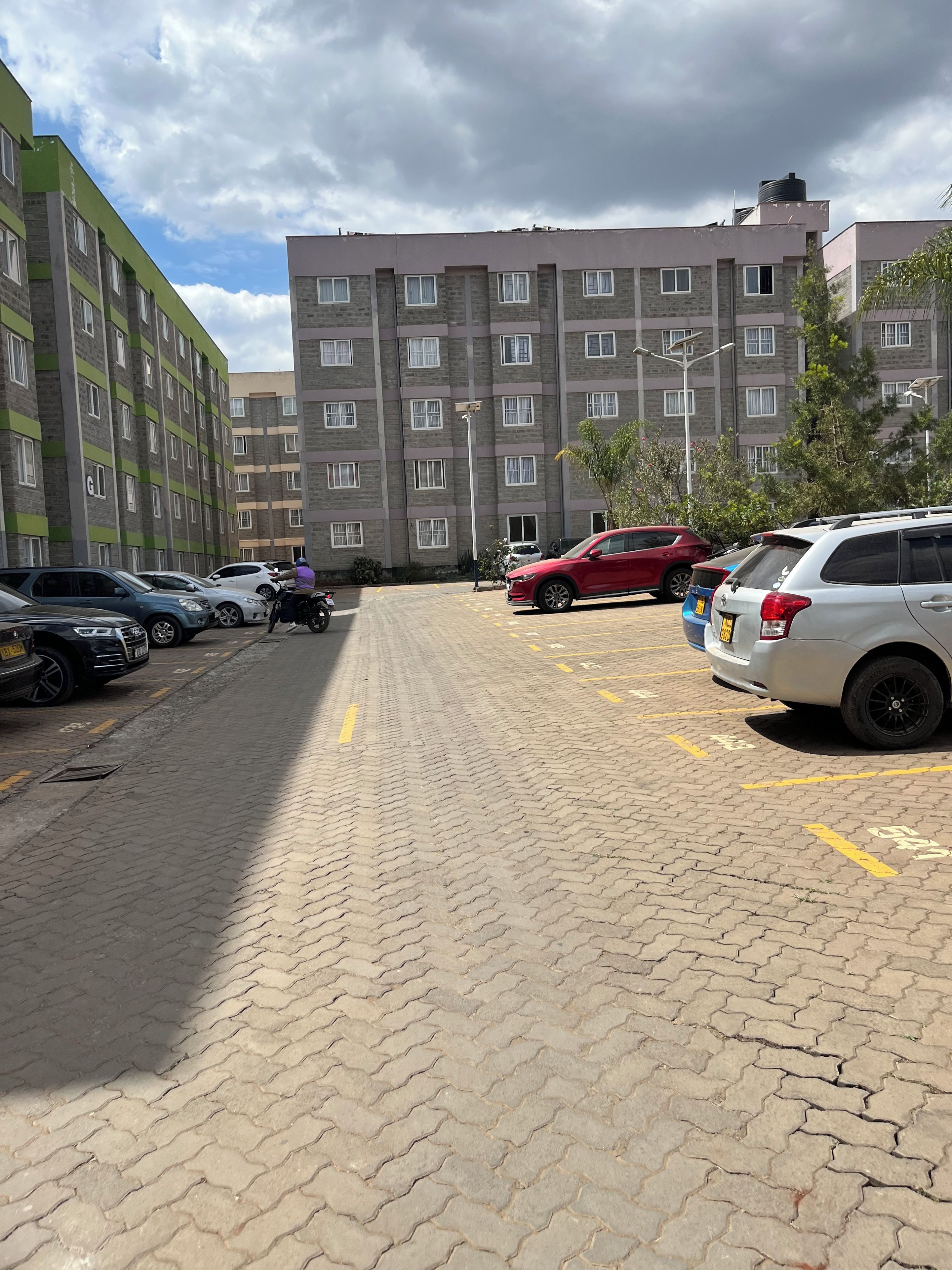 Een parkeerplaats met meerdere auto's en een gebouw met een bakstenen gevel op de achtergrond.