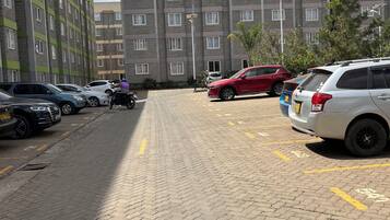 Een parkeerplaats met meerdere auto's en een gebouw met een bakstenen gevel op de achtergrond.